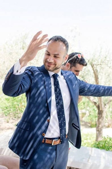 The groom opening up a bottle of champagne with his friends before his summer wedding in Sifnos island.