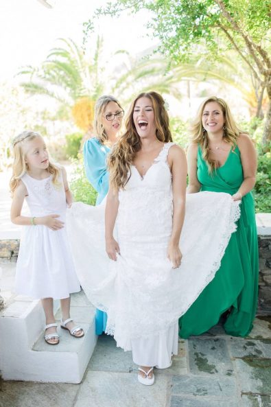 Group shot of the mother of the bride, the sister of the bride, the bride and the flower girl laughing. holding the wedding dress's train.