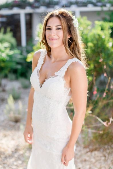 Portrait of a bride in a white lace summer wedding dress, loose curls and flower hair pin.