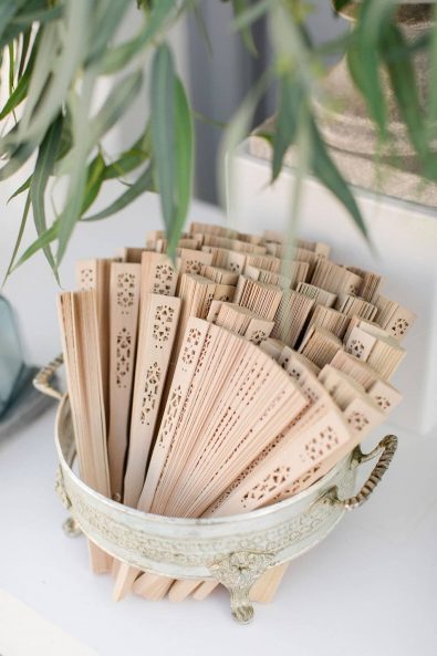 Light brown bamboo hand fans for wedding guests.