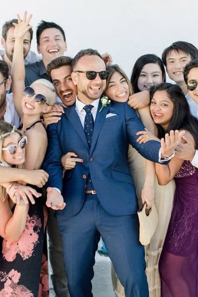 Group shot of groom and his friends in a group hug posing for a photo, all laughing and being joyous.