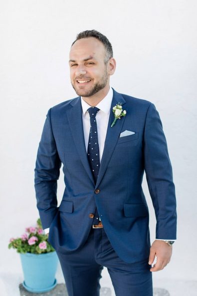 Portrait of a handsome groom in a navy blue suit with brown details and dotted necktie, before his wedding.