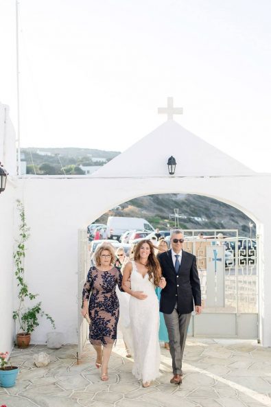 The mother and the father of the bride holding her by hand while they're entering the churchyard.