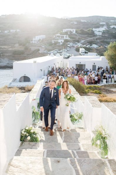 Bride and groom holding hands and walking toward the church of their wedding with all their friend and family.