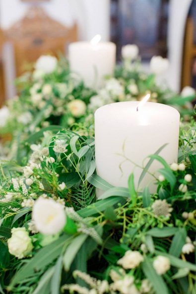 Wedding candles flower decoration with eucalyptus, roses, and hypericum berries.