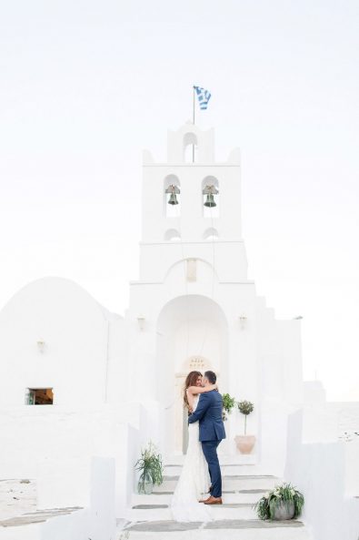 Bride and groom embracing each other in front of the church of their wedding.