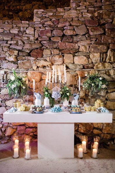 Candy bar dessert station table with sweet treats, flowers, and candles for a destination wedding in Sifnos, Greece.
