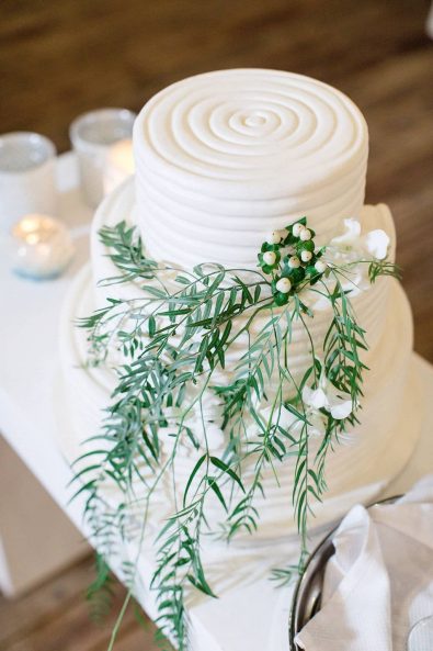 Elegant and simple total white wedding cake with greenery and hypericum berries.