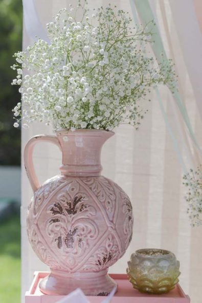 Pink vase baptism flower arrangement with baby's breath flowers.