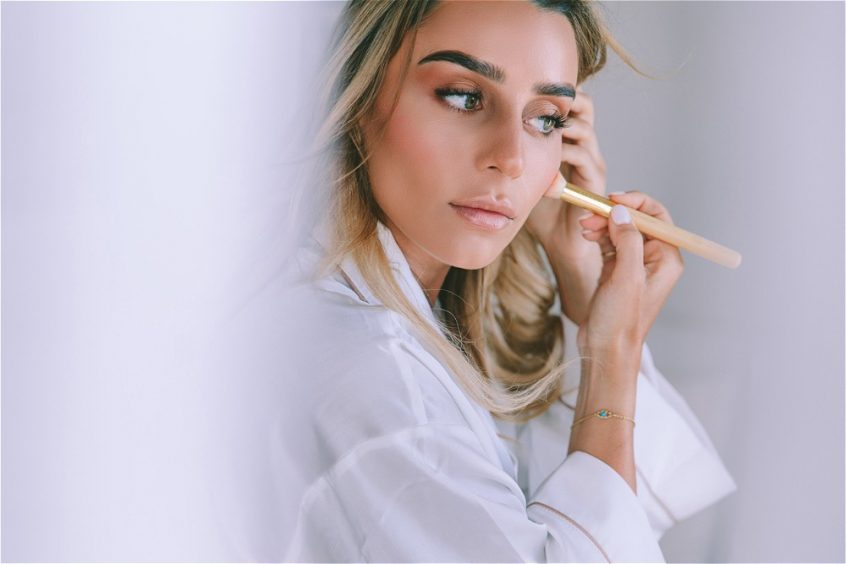 Blonde bride putting makeup for her wedding