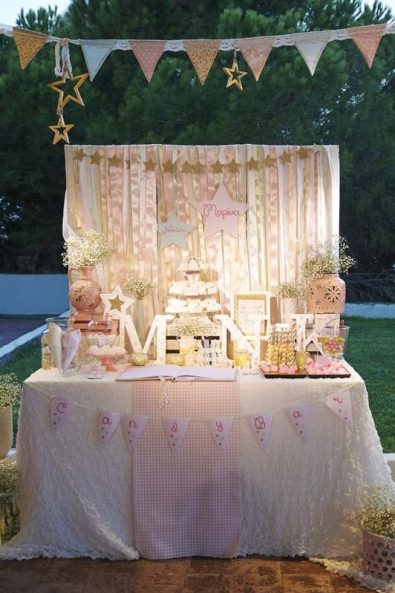 Greek orthodox baptism - Shabby chic candy bar with a golden backdrop, decorative letters, hanging star decorations, flag garland, and christening sweets.