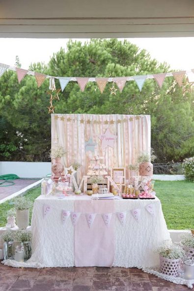 Greek orthodox baptism Candy Bar with a ribbon backdrop, star decorations, baby's breath flowers, and christening sweets.