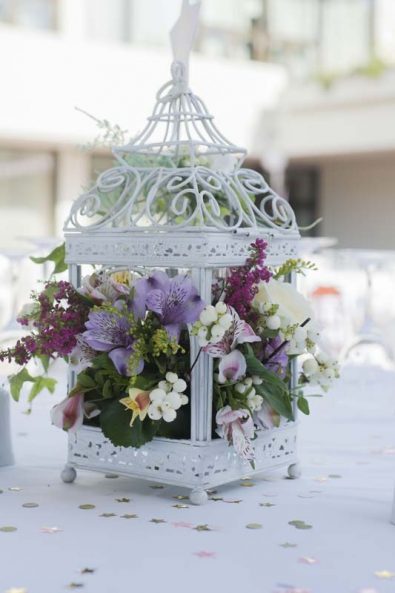 Table centerpiece with alstroemeria flowers and hypericum berries in a white metal lantern for a Greek orthodox baptism.