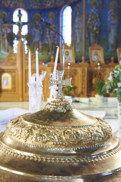 Baptistery with flower arrangement and christening candle in Faneromeni Church, Vouliagmeni for a Greek orthodox baptism.