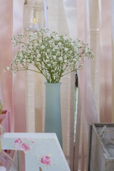 Christening flower arrangement with baby's breath in a mint vase.