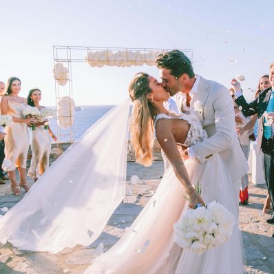 Destination weddings: Groom kissing bride at their wedding in Paros
