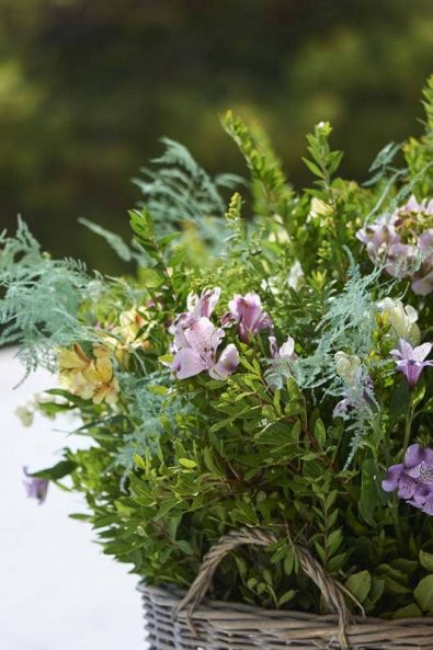Baptism flower arrangement in a basket with alstroemeria and greenery.