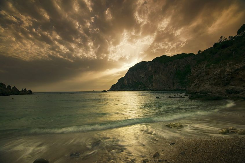 sunset with rocky hill and sea in corfu