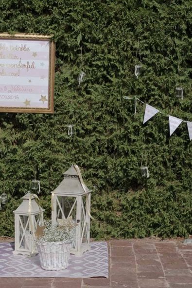 Baptism decoration for baby girl with party flag garland, quote poster, candle lanterns and baby's breath flowers.